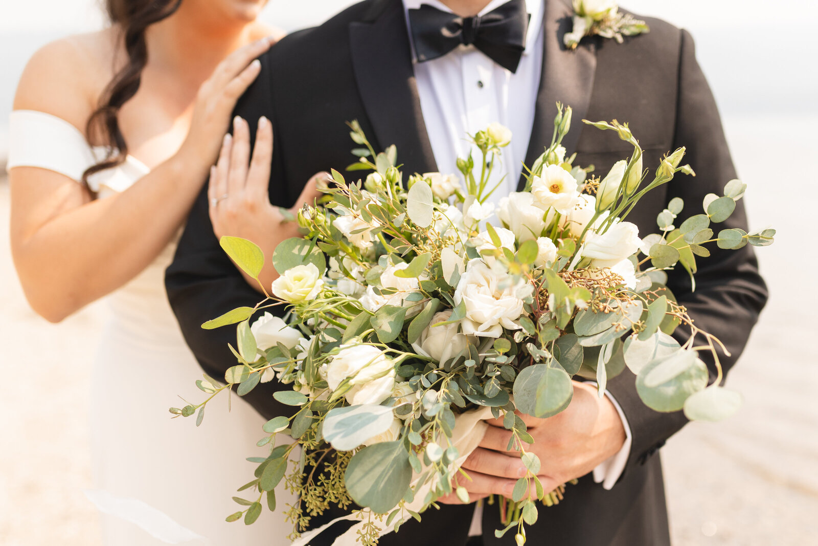 groom holding flower bouquet with bride holding his arm