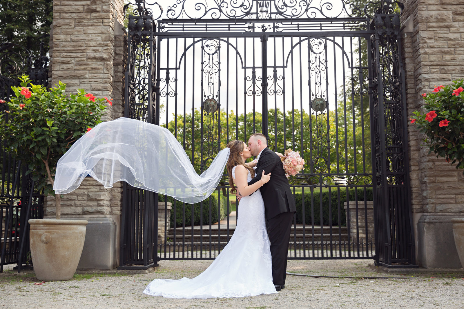 bride and groom kissing with veil blowing in the wind