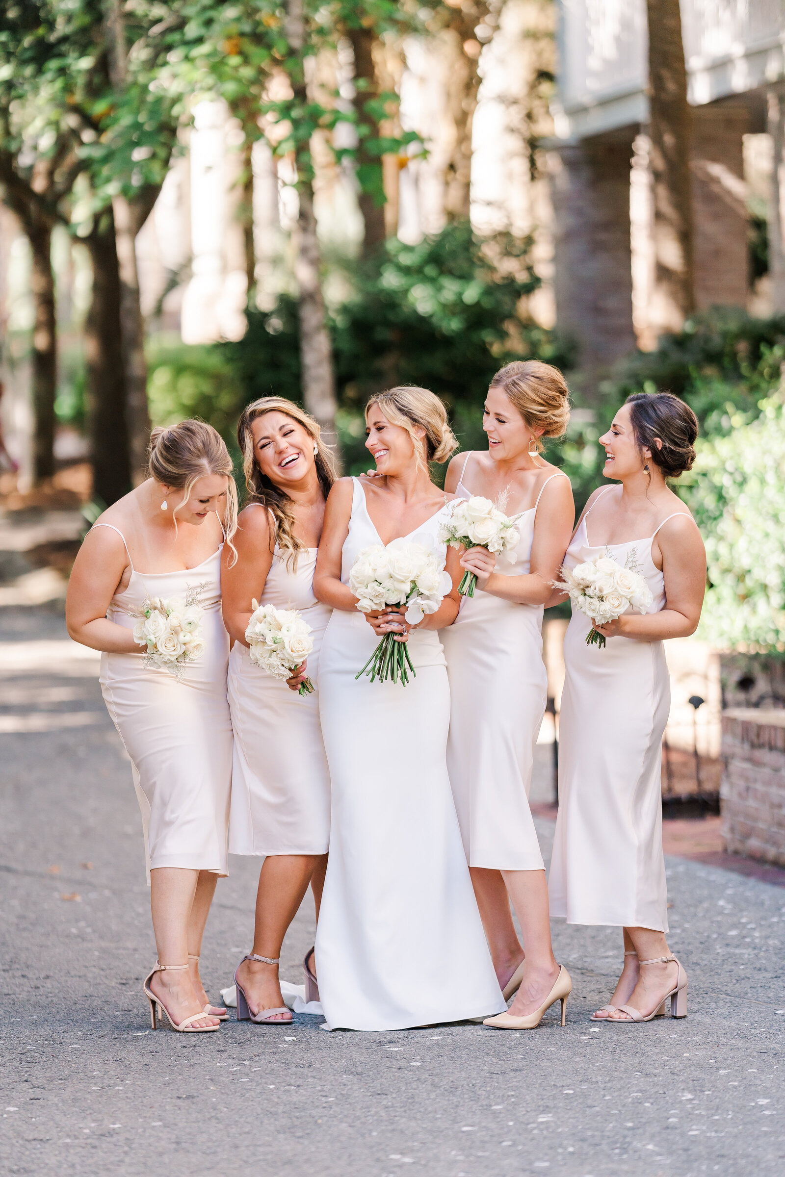 Bride and her bridesmaids laughing together in street