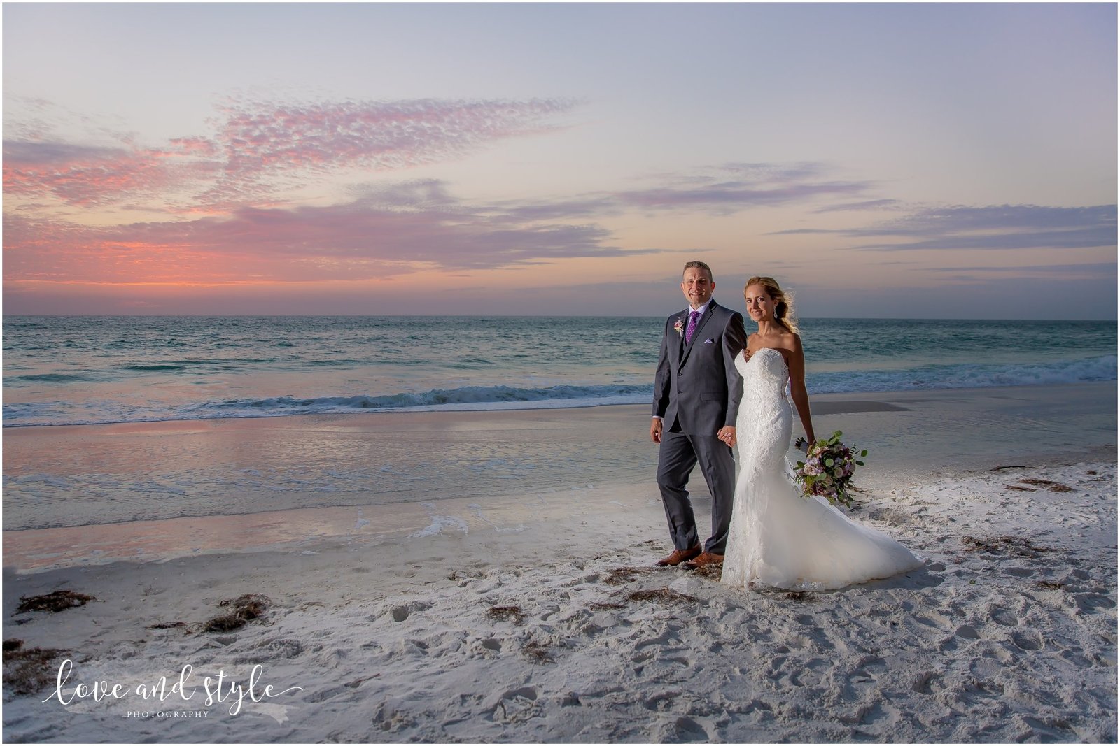 Bride and Groom walking on the beach at sunset in front of The Beach House on Anna Maria Island
