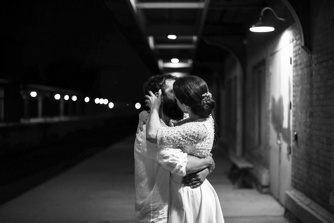 Bride and groom kiss along the train tracks at the Brewerie at Union Station