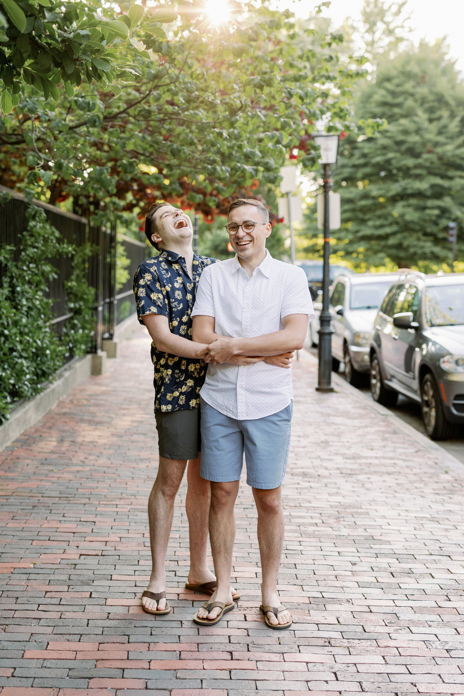 Couple standing on a brick sidewalk with their arms around each other.