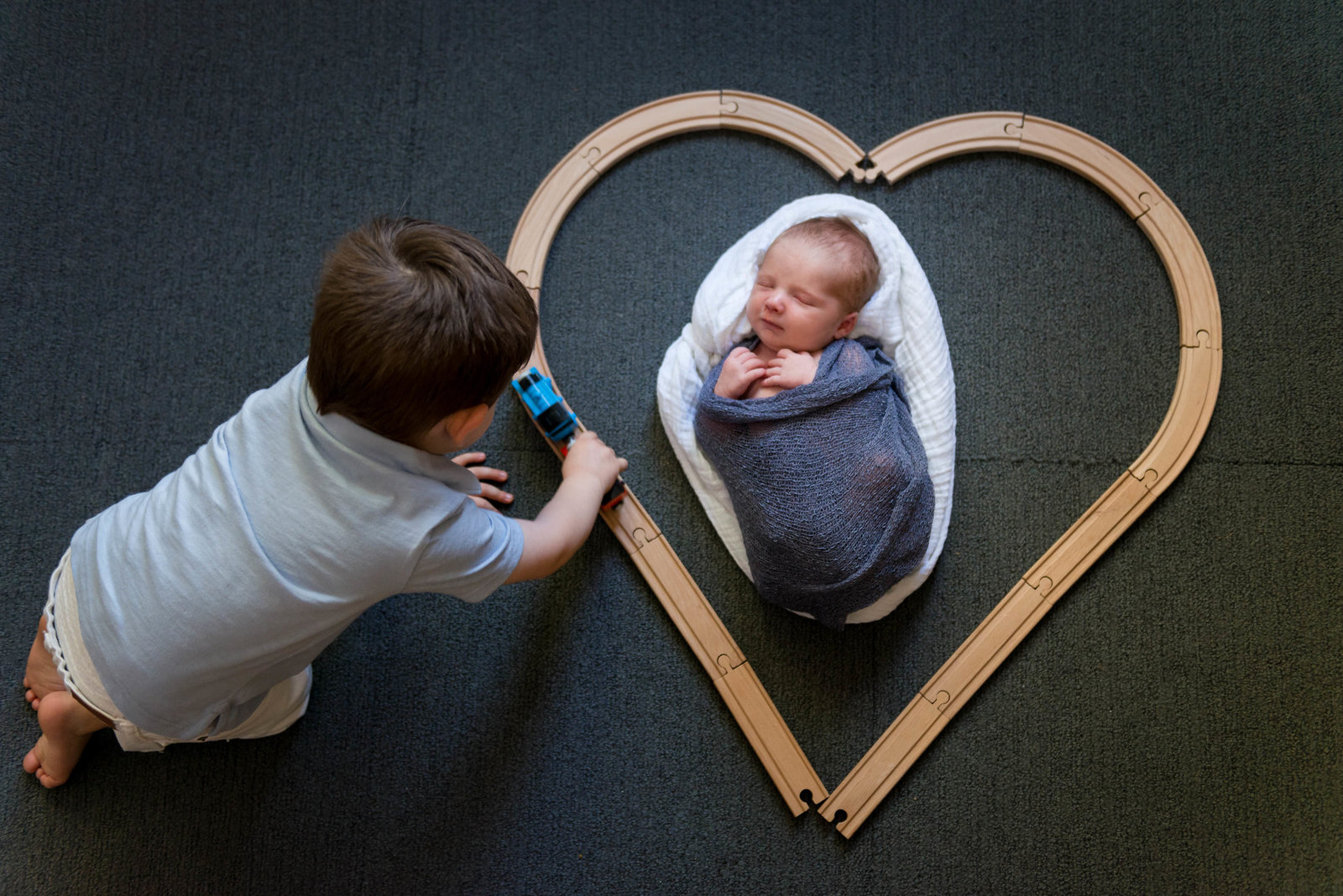 Sibling with train and newborn at home lifestyle session