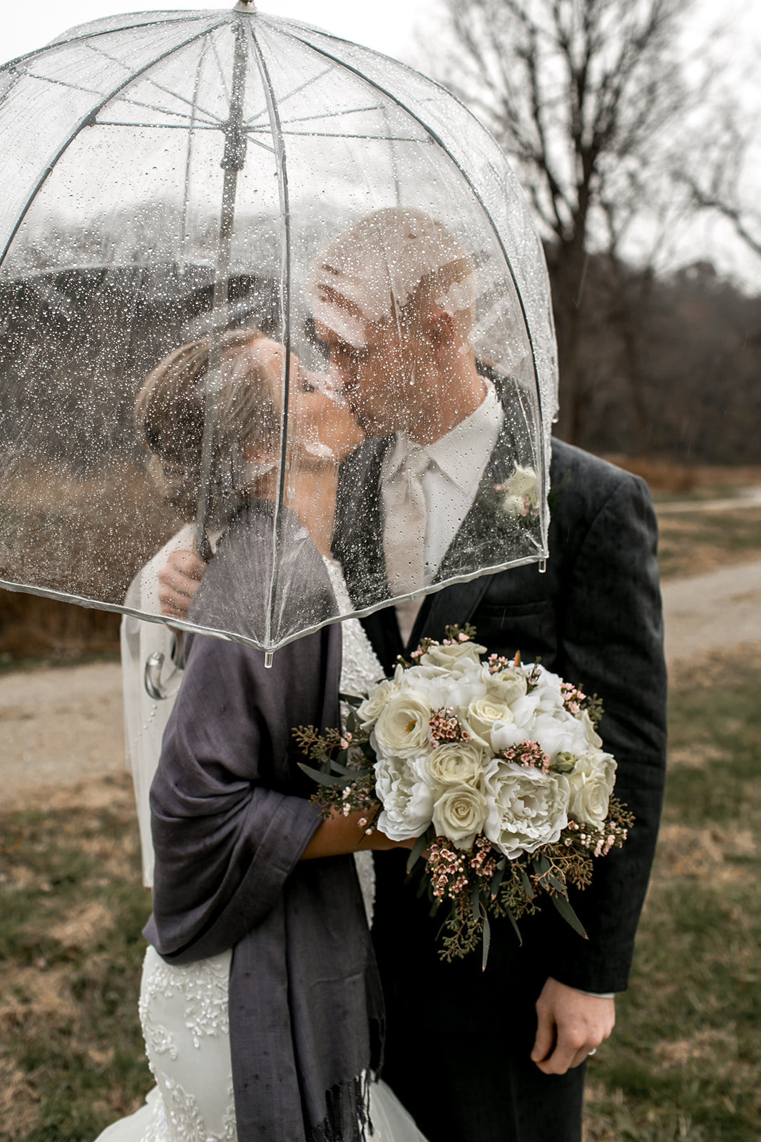 Des Moines Iowa Wedding couple under an umbrella while it's raining.