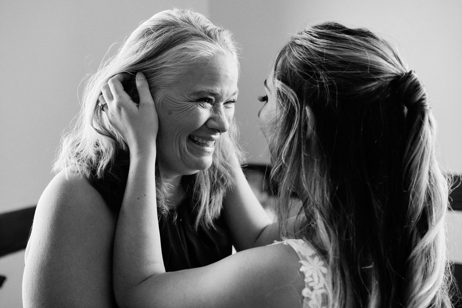 Bride holds her mothers face as mom sees the bride for the first time