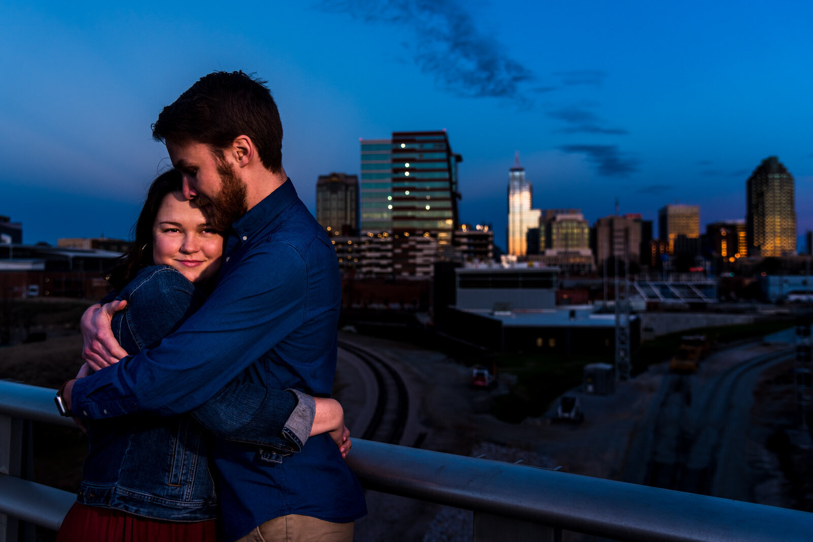 Couple embraces on Boylan Bridge overlooking the downtown Raleigh skyline