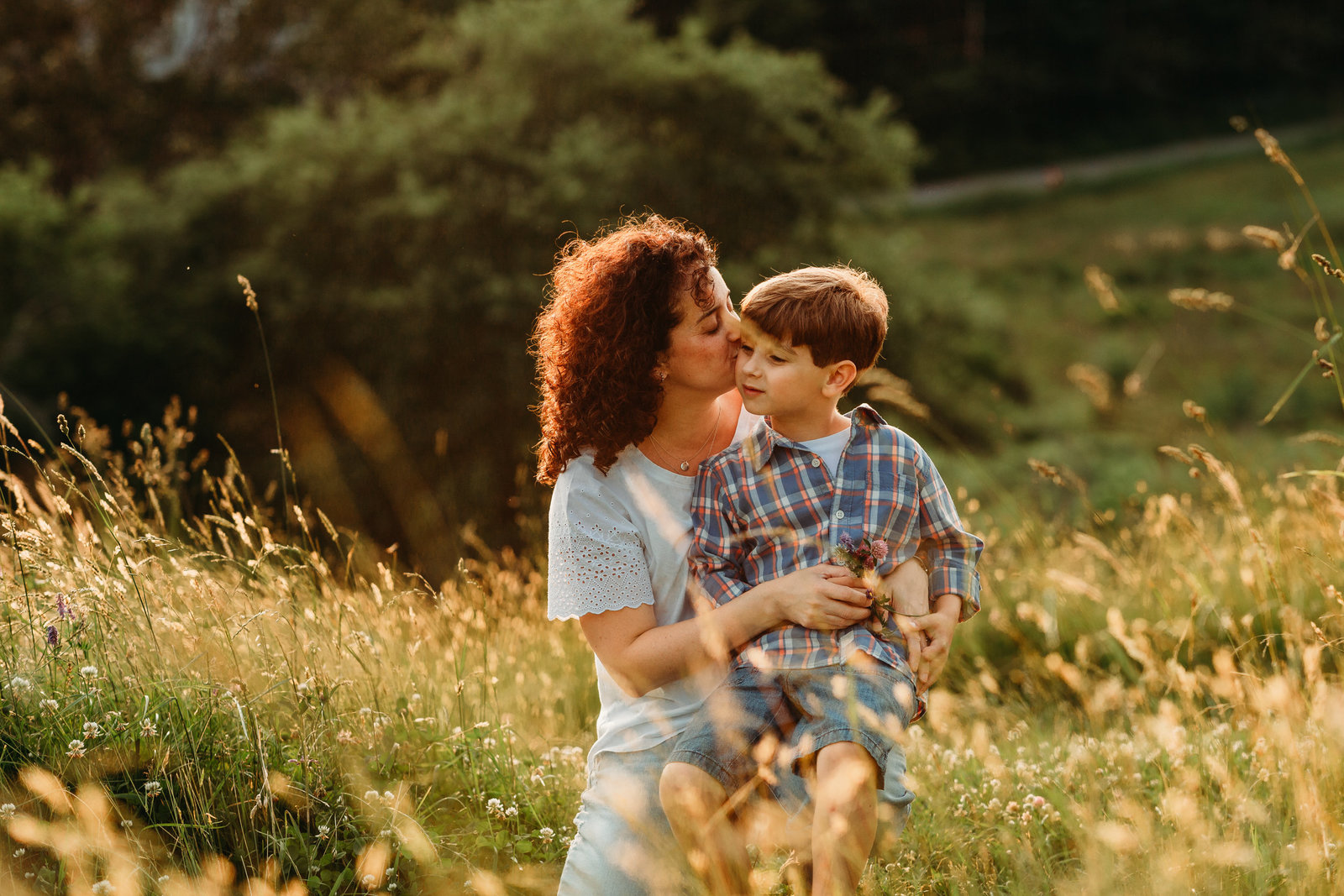 mom snuggles older son at sunset in field in southborough ma