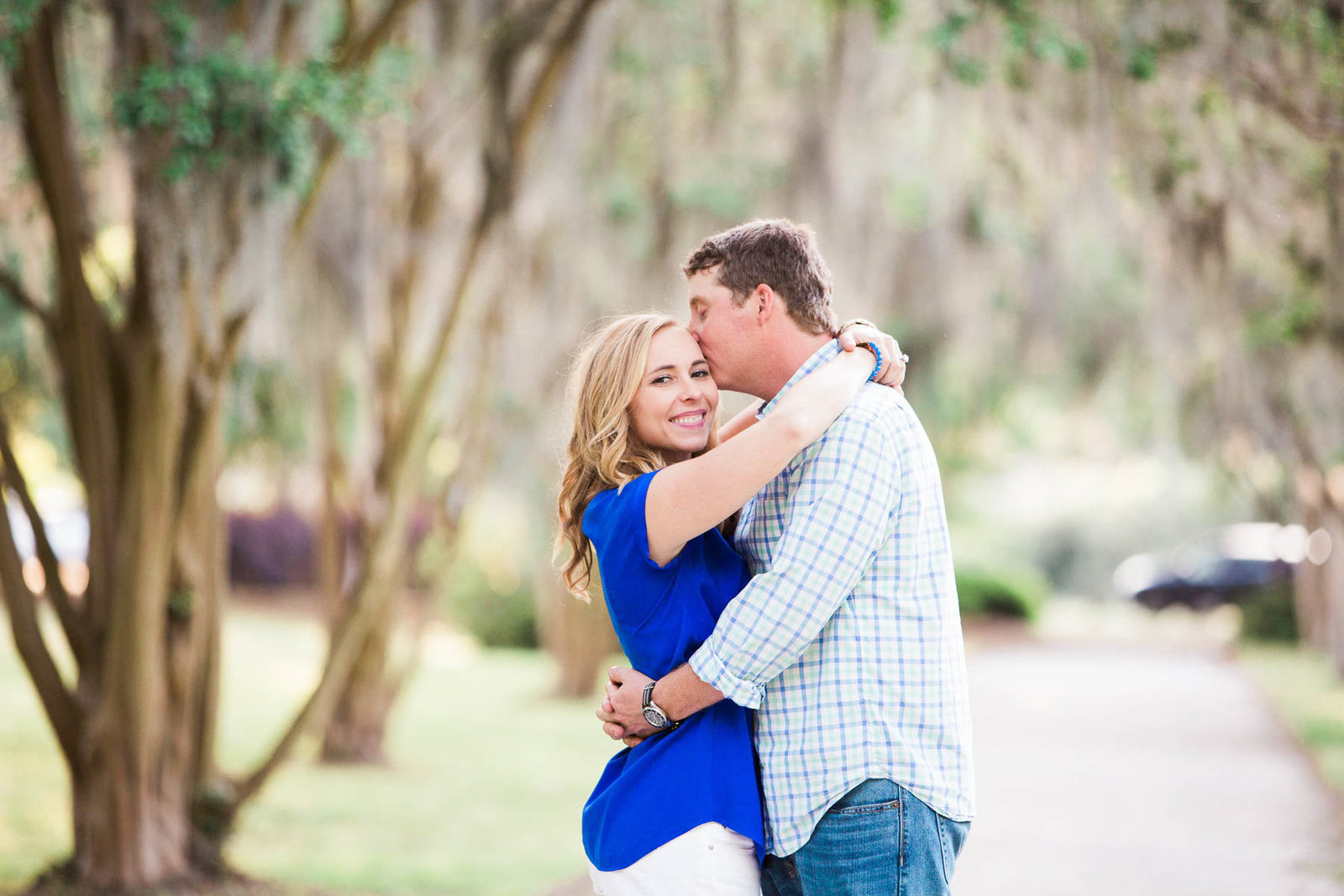 Engaged couple stand in pathway full of trees and spanish moss, Hampton Park, Charleston Engagement Photographer.