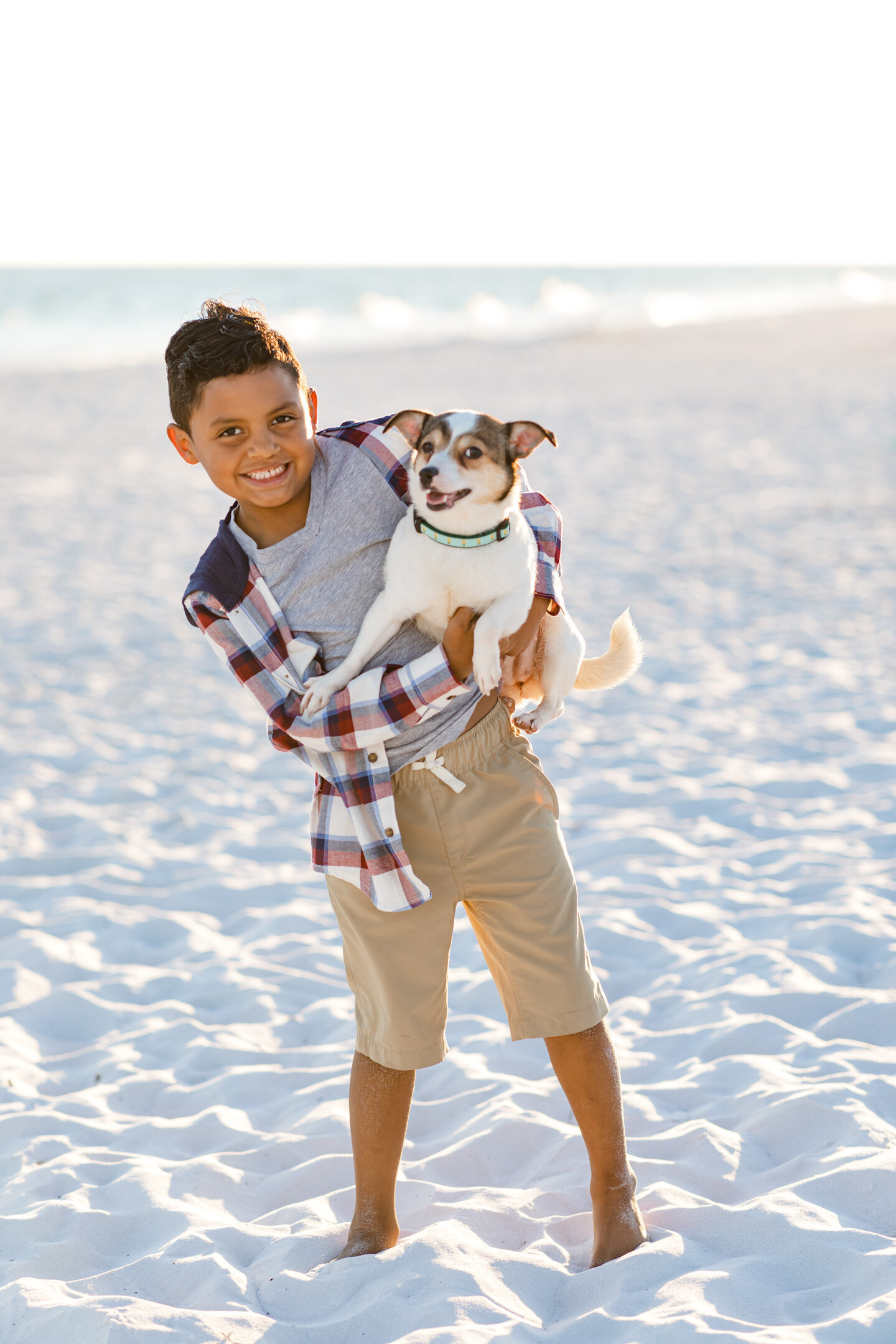 Little boy holding his dog during Pensacola Beach photo session.