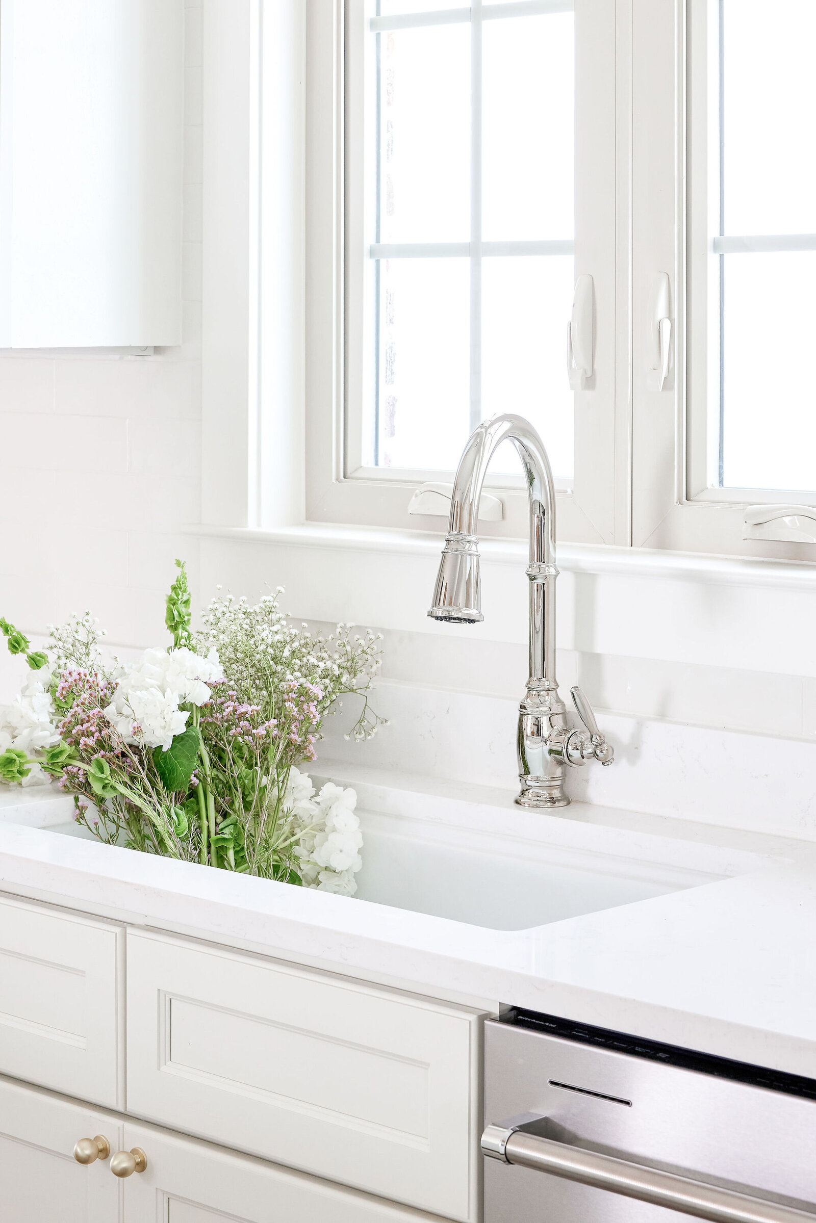 cocoloba homes cockrell ave kitchen farmhouse siink with flowers in it and silver faucet