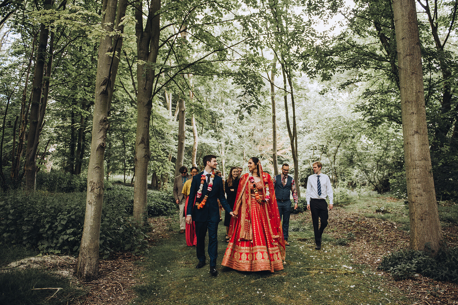 Bride and groom walking through their woodland wedding in Cambridge