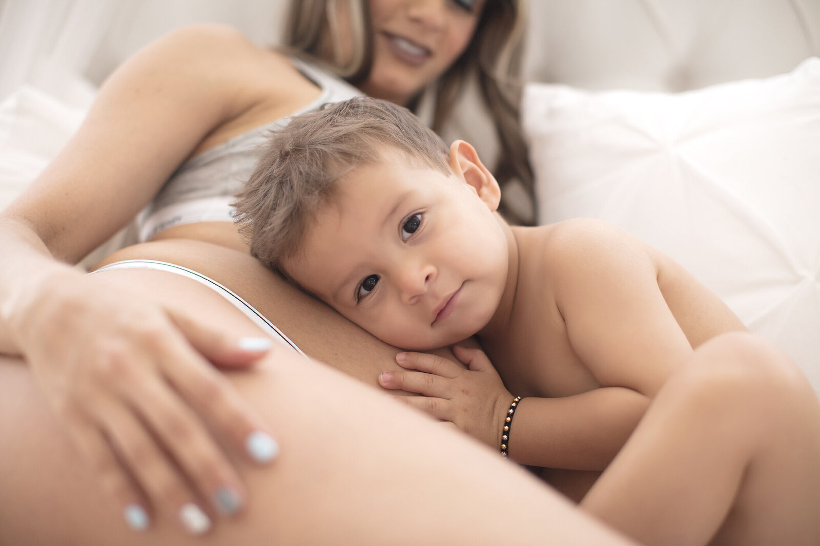 Toddler with head on mothers baby bump.