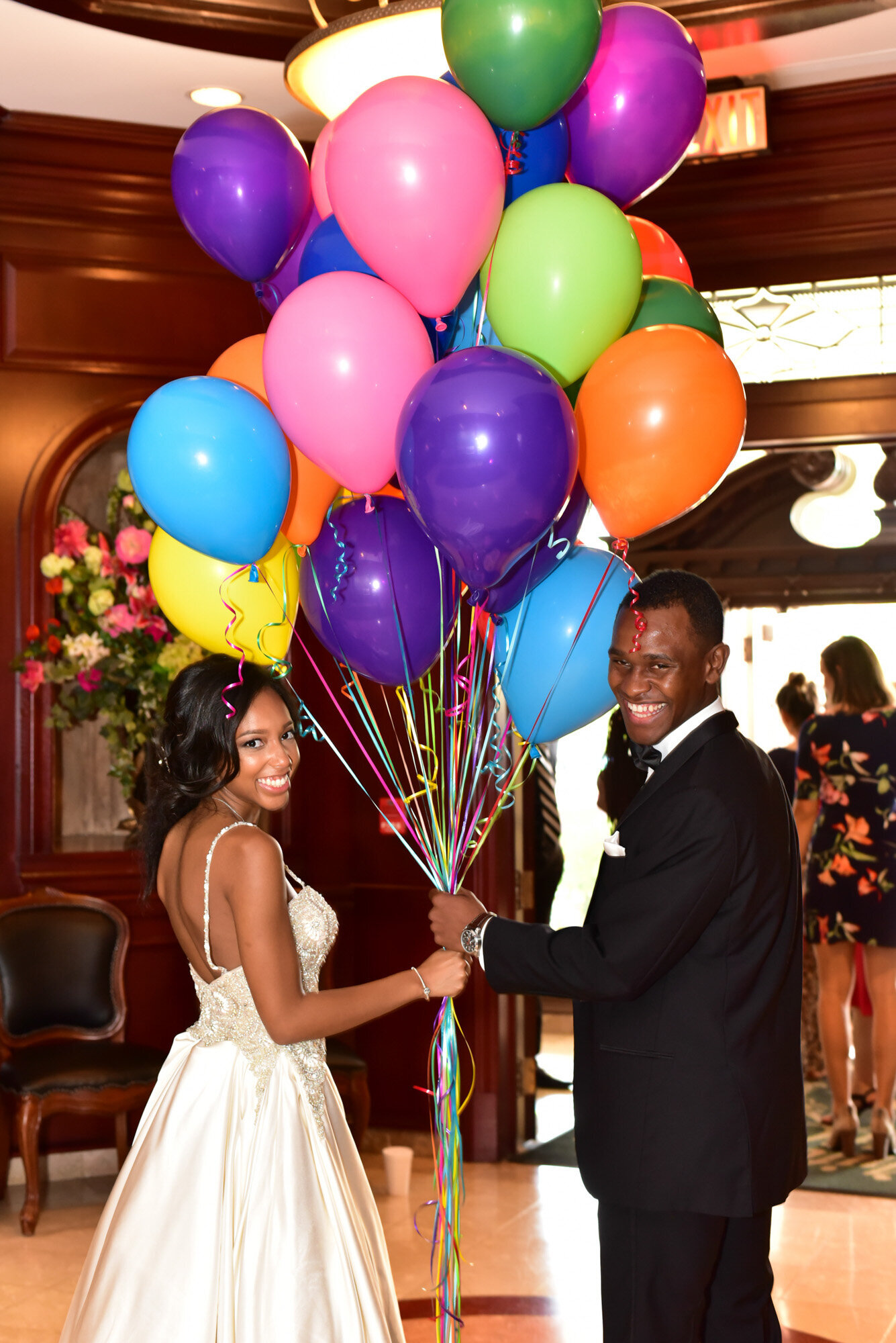Bride and groom holding the strings of balloons while both smiling