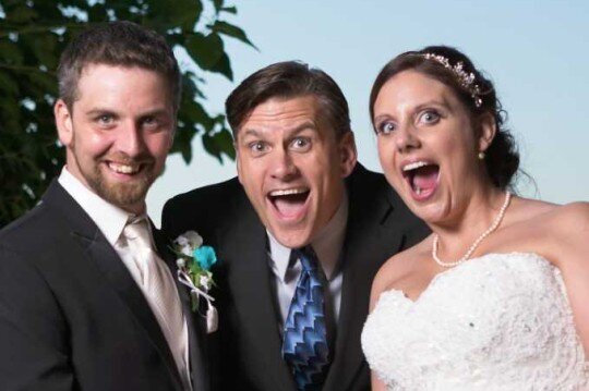 Bride, groom, and officiant smile excitedly after wedding