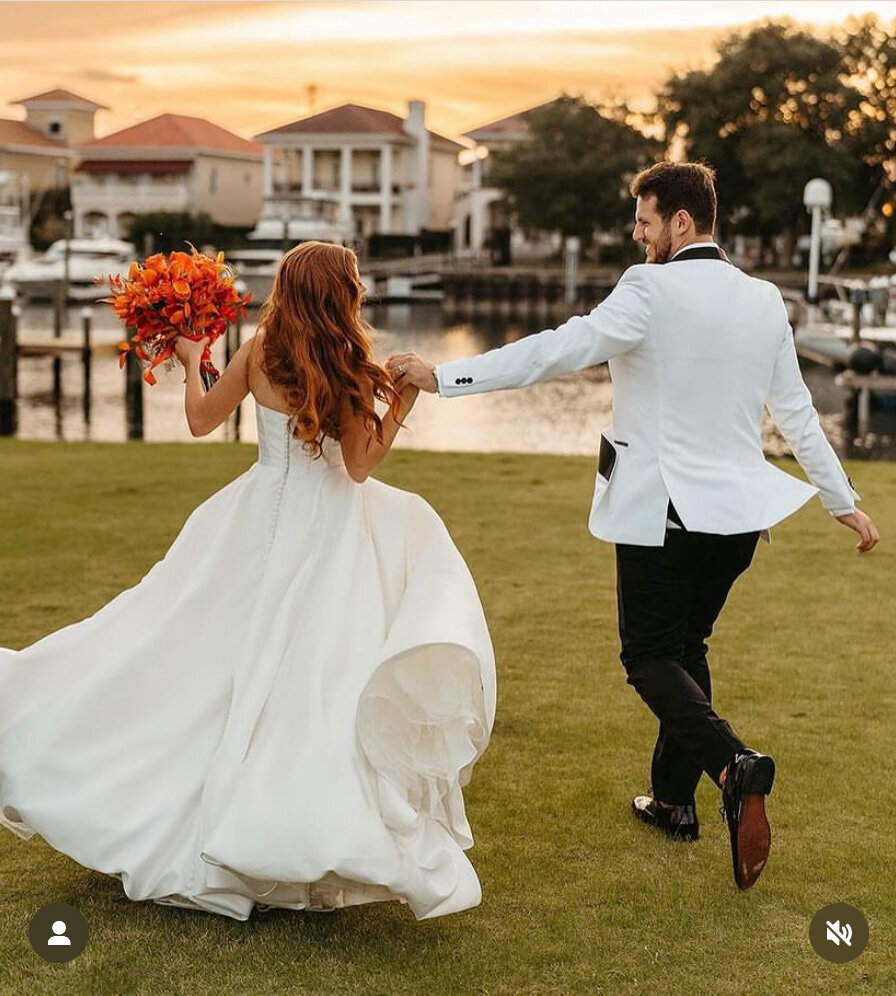 Photo Op on Lush Green Lawn at Palafox Wharf Waterfront with Red Headed Bride with Burnt Orange Florals by Fiore in Pensacola FL