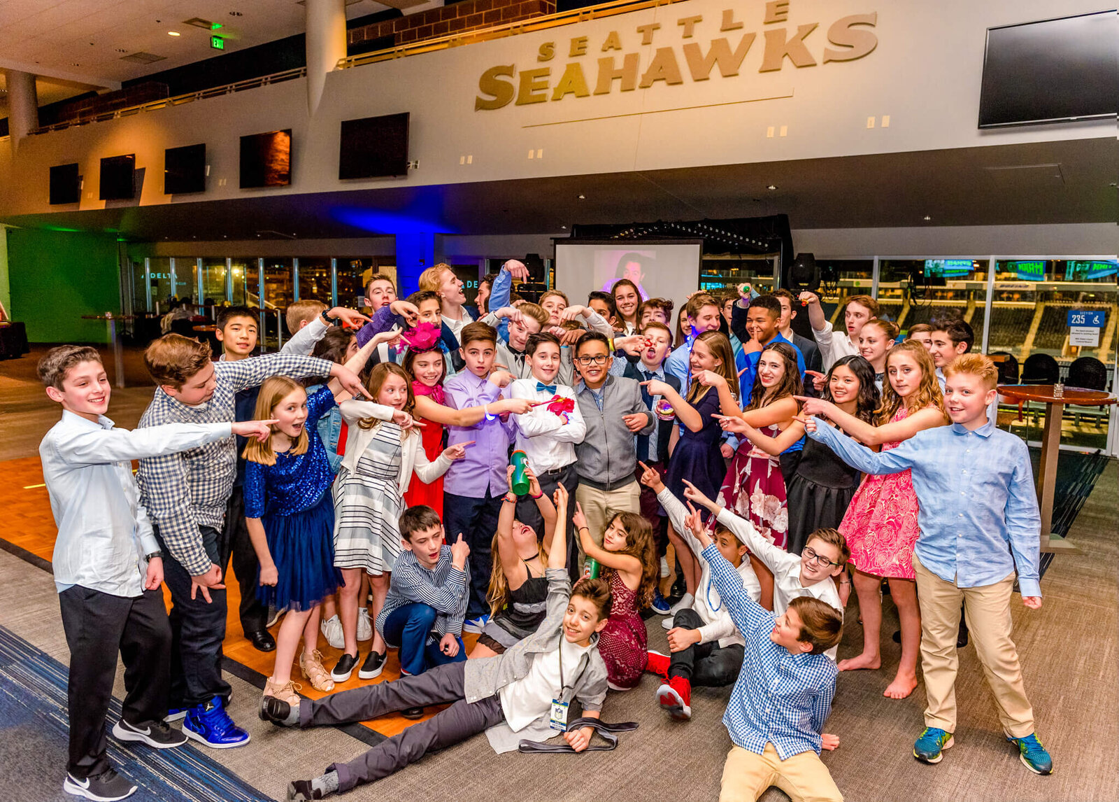 A large group of friends point to the mitzvah boy in the middle during a Bellevue Bar and Bat Mitzvah Photography session