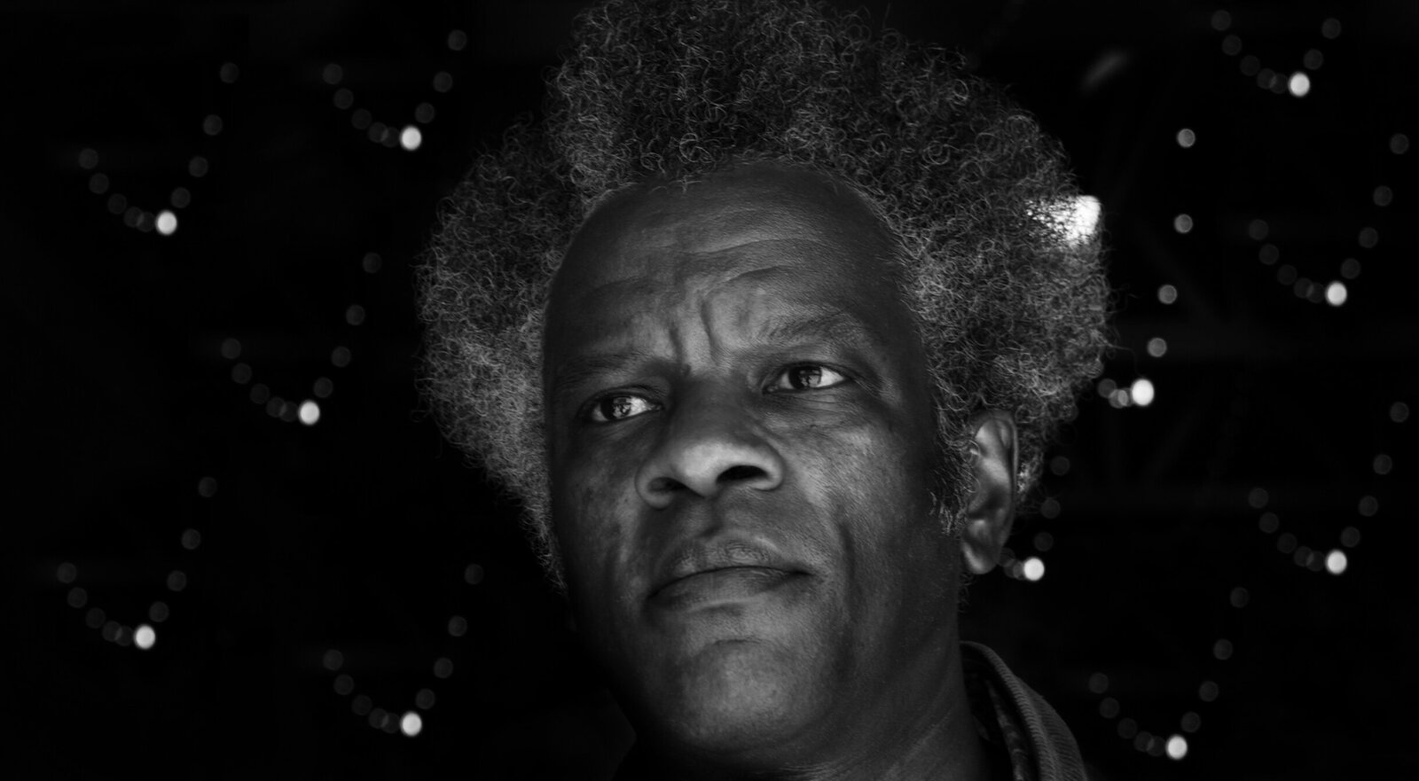 Musician portrait black and white Los Angeles closeup looking off camera in front of small dotted lights
