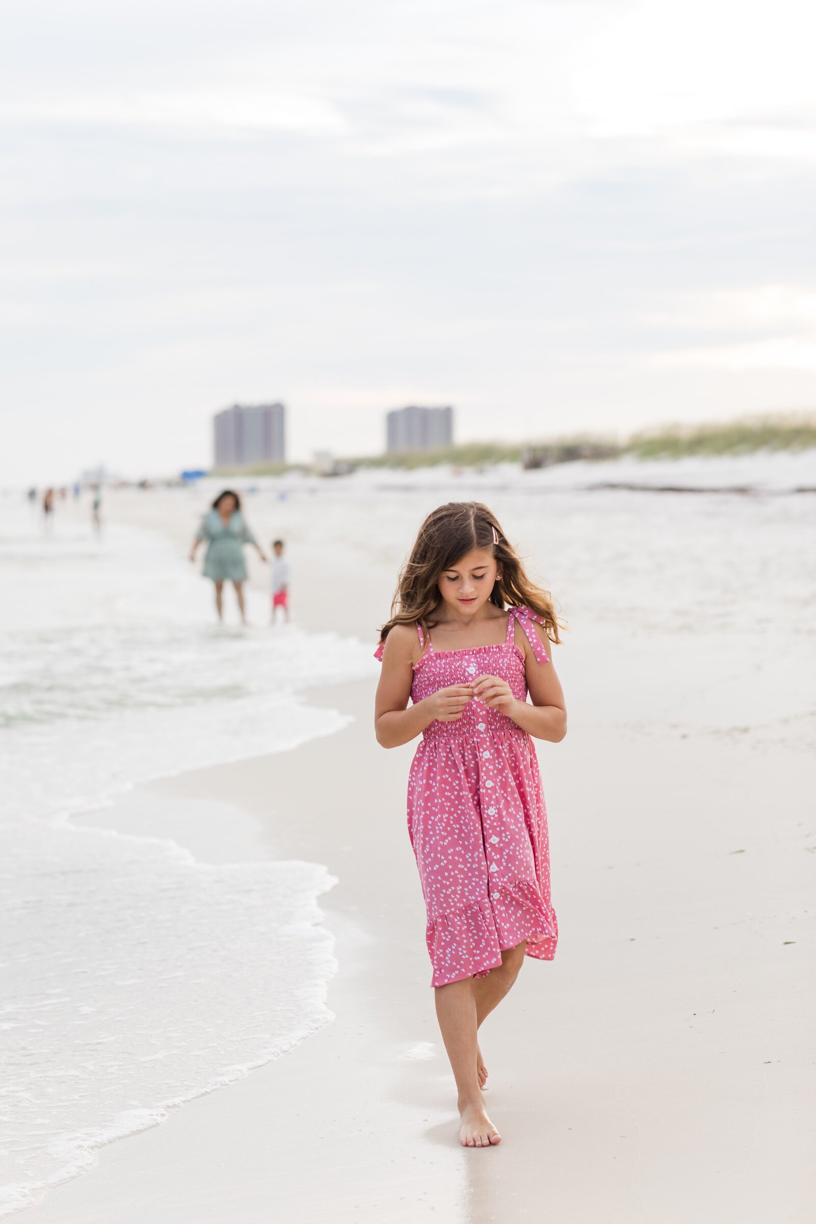 Pensacola Beach vacation family photo session . Daughter walking  at the edge of the water.