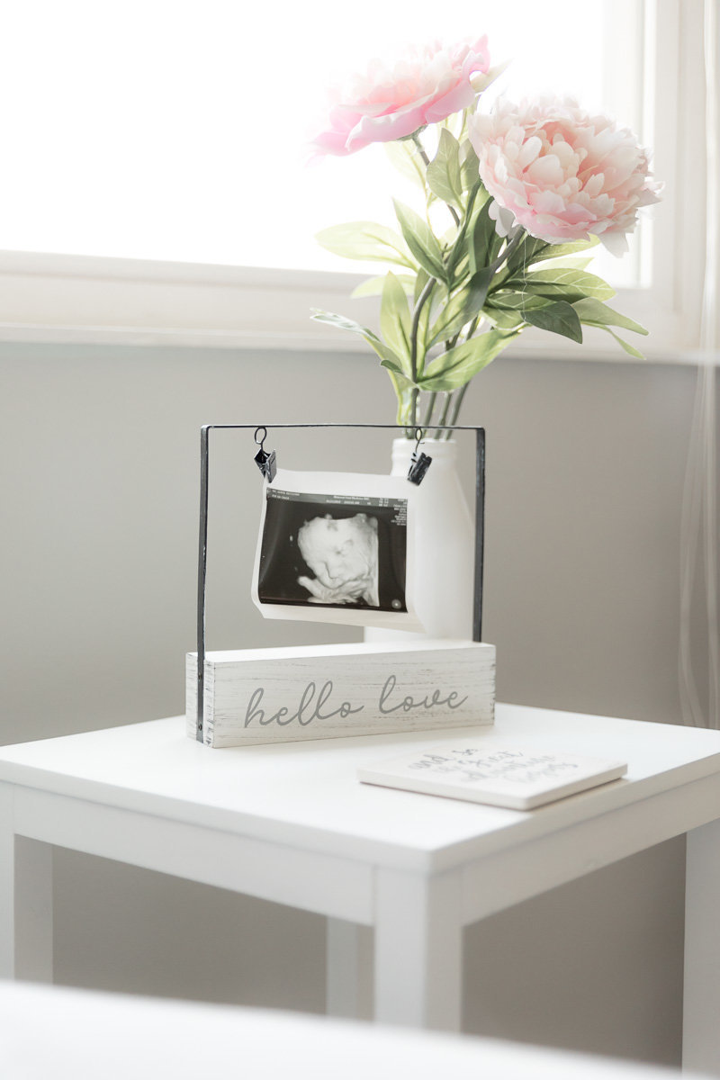 Ultrasound pictures and flower on side table in front of nursery window