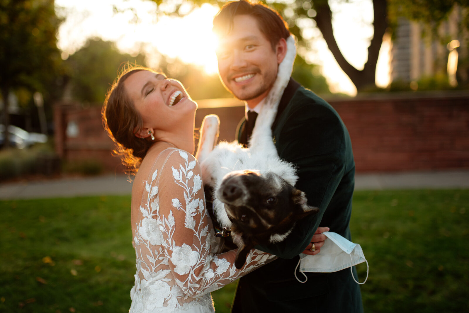 bride and groom holding their dog like a baby and laughing