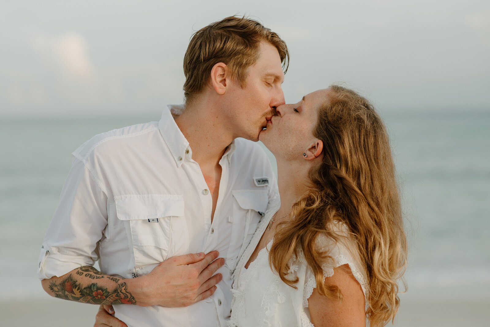 Pensacola Beach vacation family photography session .  Couple kissing  on the beach.