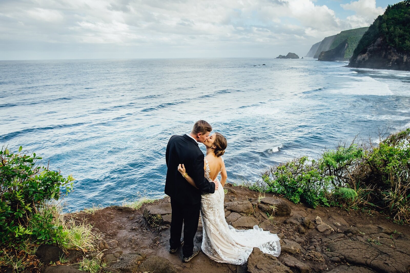 bride and groom kissing on cliff after their elopement at pololu valley
