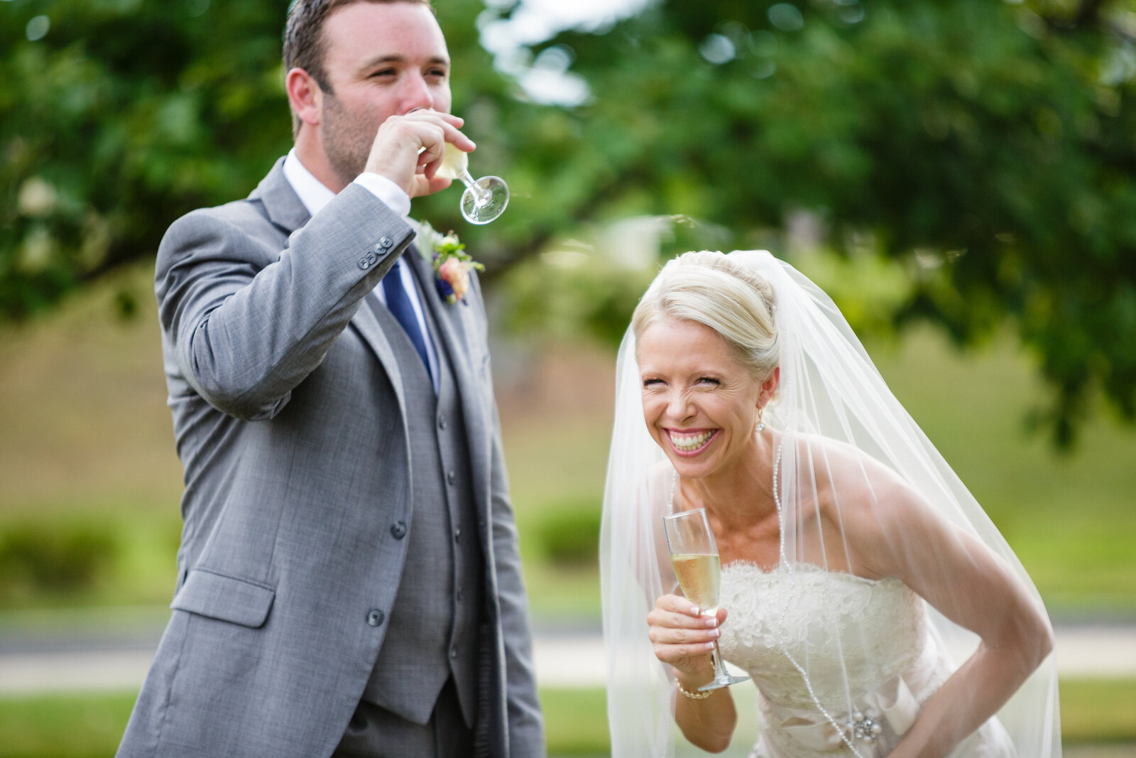 bride and groom laughing while drinking champagne