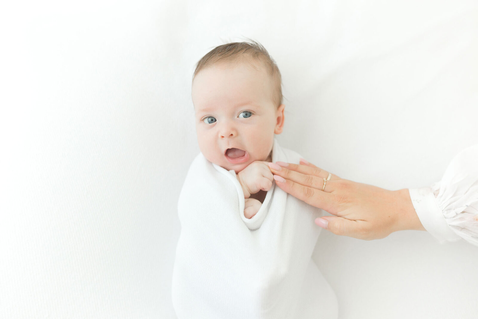 Neugeborenenfotoshooting alles in weiß mit wachem Baby.
