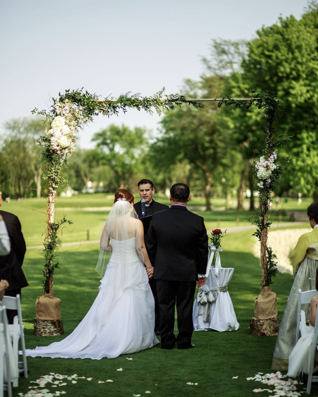 Bride and groom hold hands during wedding ceremony outdoors