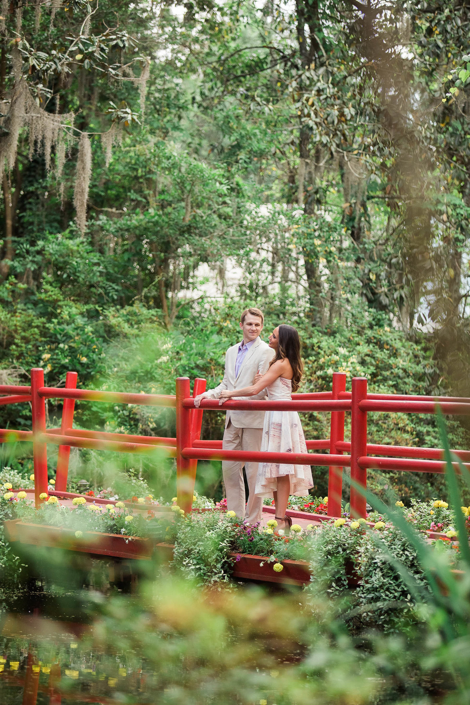 Engaged couple stand on a red bridge, Magnolia Plantation, Charleston, South Carolina