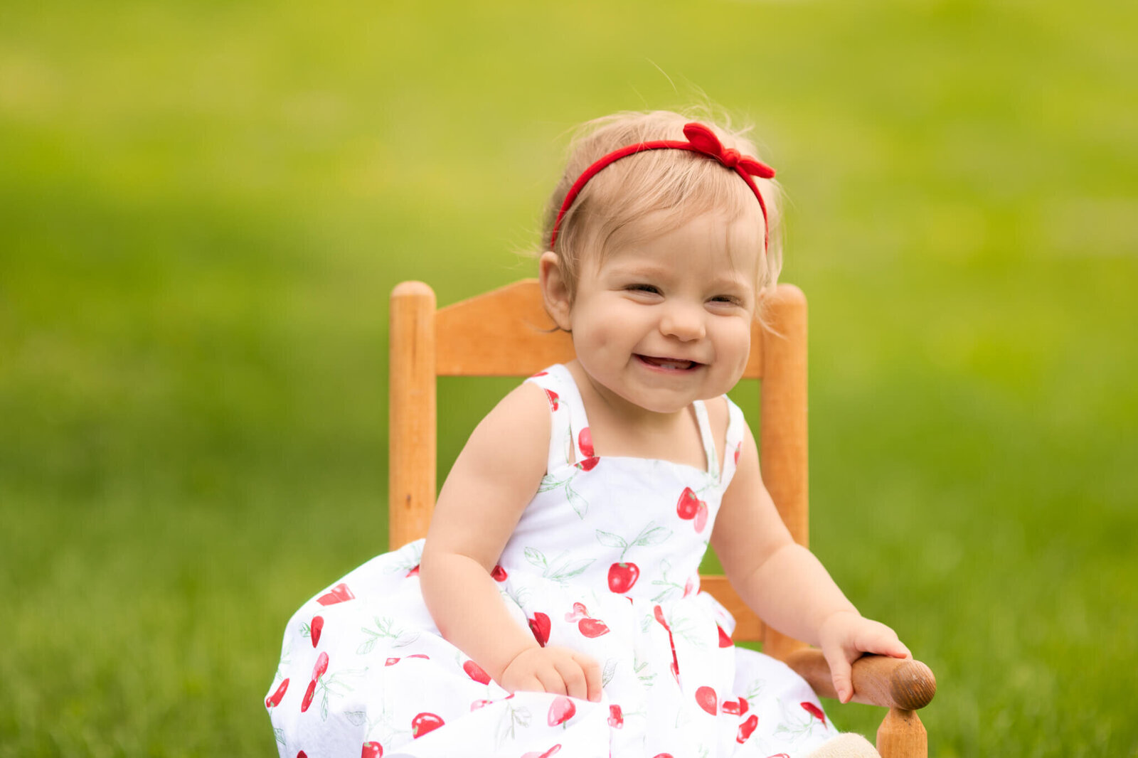 One year old girl sitting in a rocking chair in grass