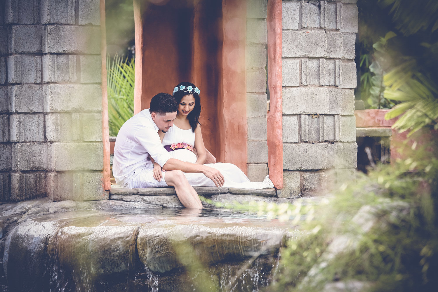 Pregnant couple sit together in idyllic setting. Photo by Ross Photography, Trinidad, W.I..