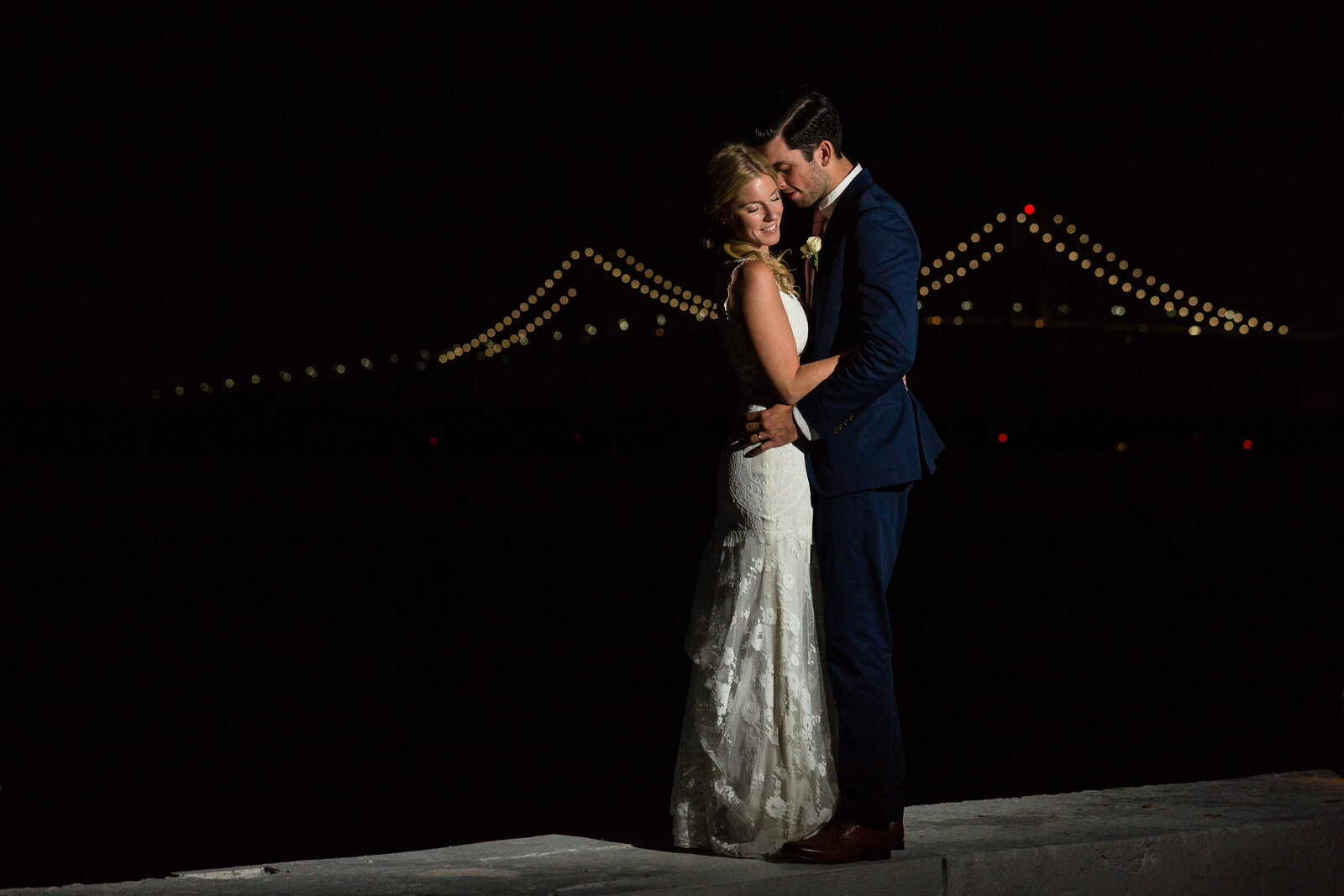 bride and groom night portrait in front of newport bridge