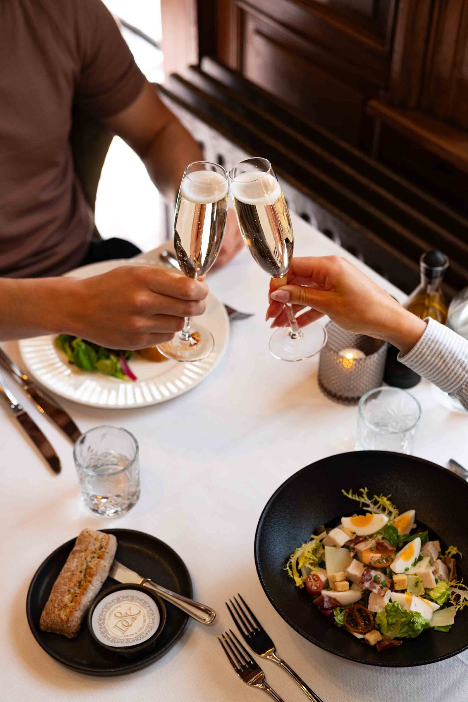 proostend koppel met glazen champagne en vers bereid eten in restaurant 