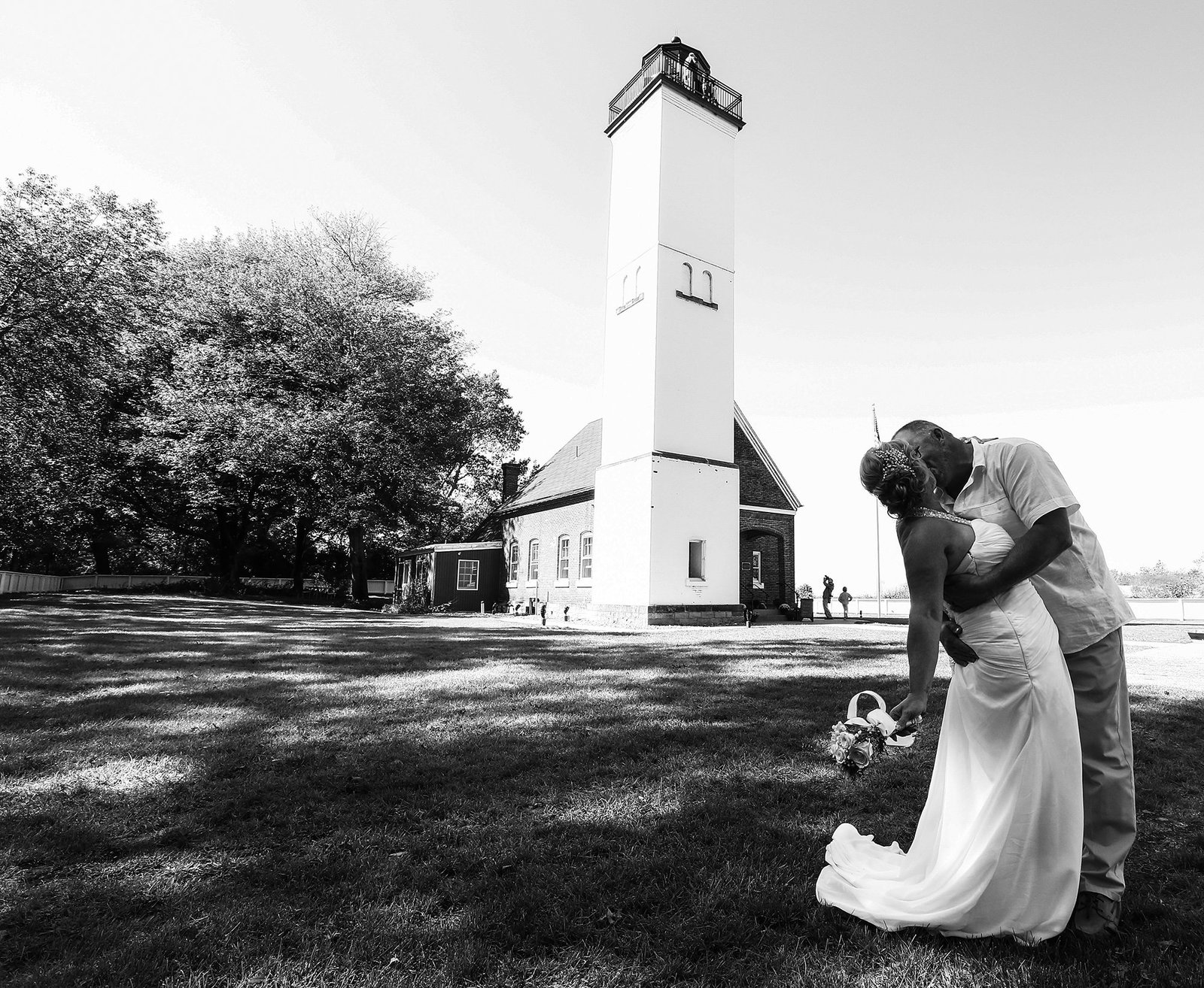 Bride and groom kiss in front og lighthouse on Presque Isle State Park