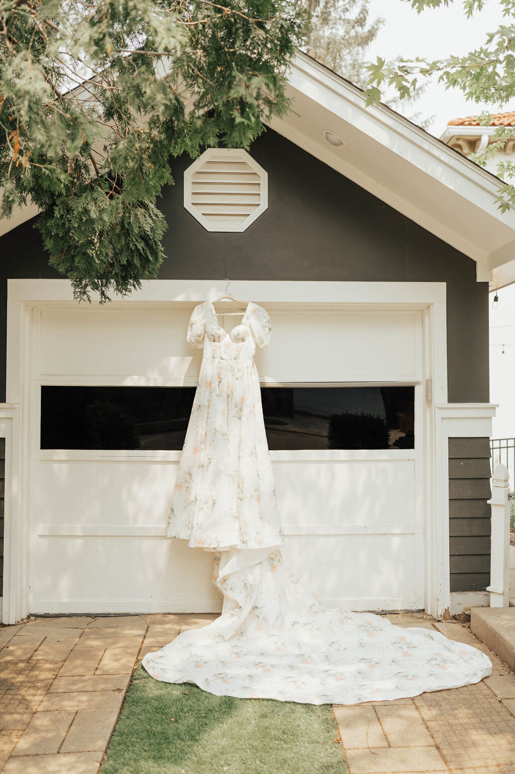 Floral backyard wedding dress hanging on garage