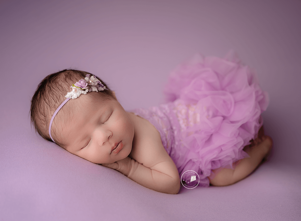 newborn baby in purple on tummy posed by Boca Raton newborn photographer