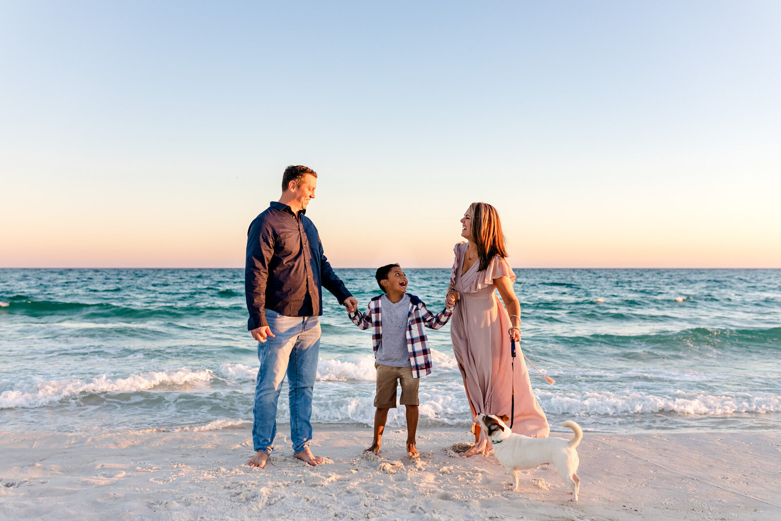 Family laughing during photo session on Pensacola Beach at sunset.