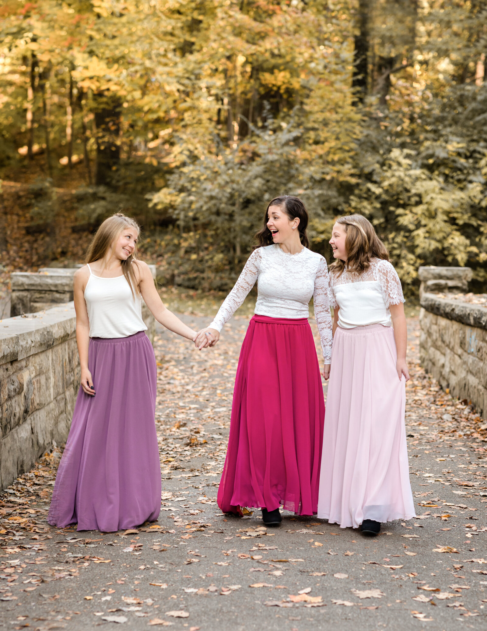 mom and two daughters walking and laughing at park for family photos