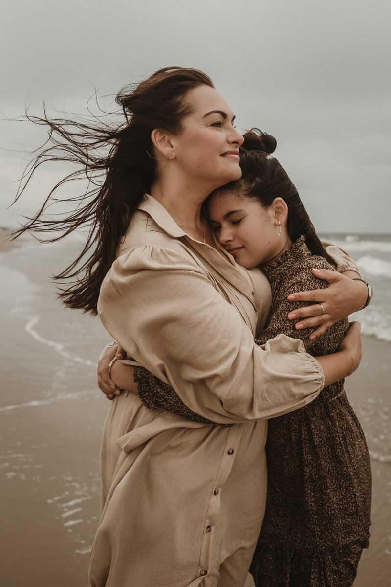 moeder en dochter omhelzen op het strand