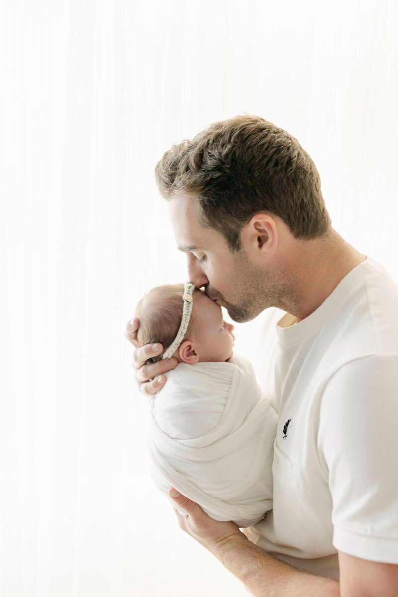 Dad kissing newborn baby taken by nj newborn photographer