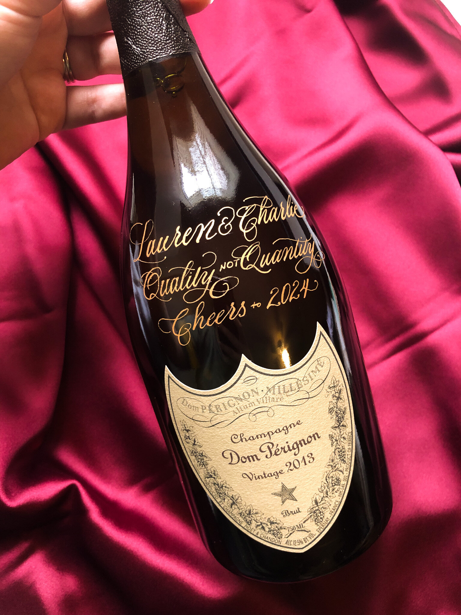 bottle of Dom Perignon  with gold calligraphy against a red silk background