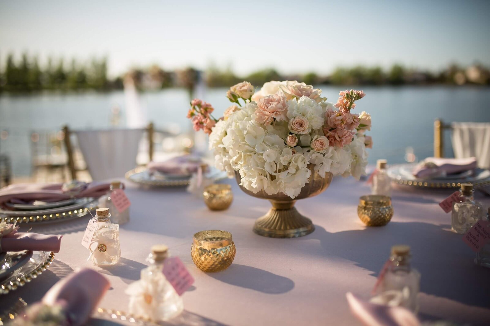 Wedding reception table with flowers in the middle and decorations that are mostly pink, captured by wedding photographer sacramento, ca philippe studio pro.