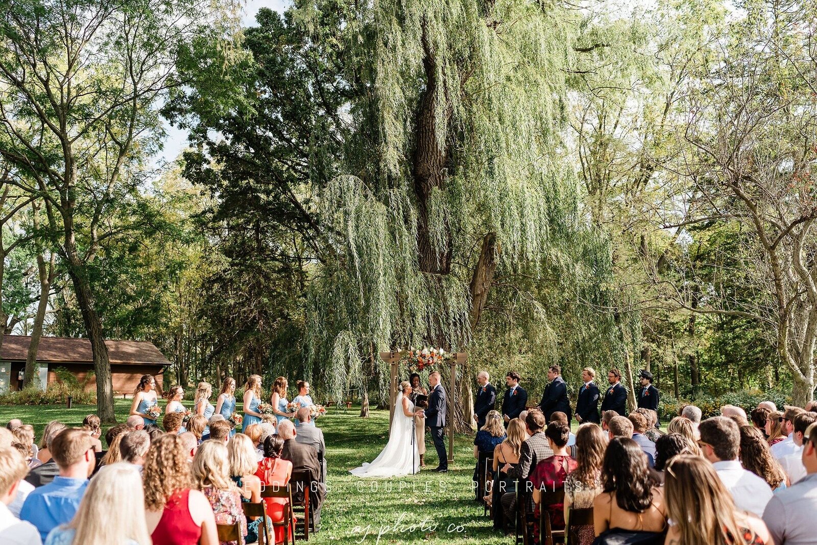 outdoor wedding ceremony under the willow tree at barnwood events in madison, winconsin,.