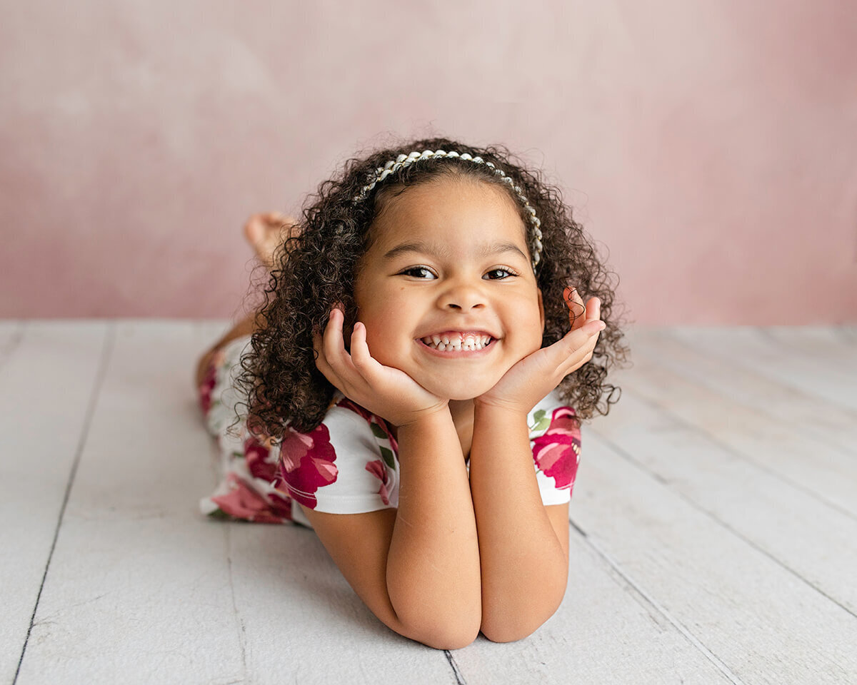 Little girl posed with chin on hands smiling, Child Photographers Bettendorf