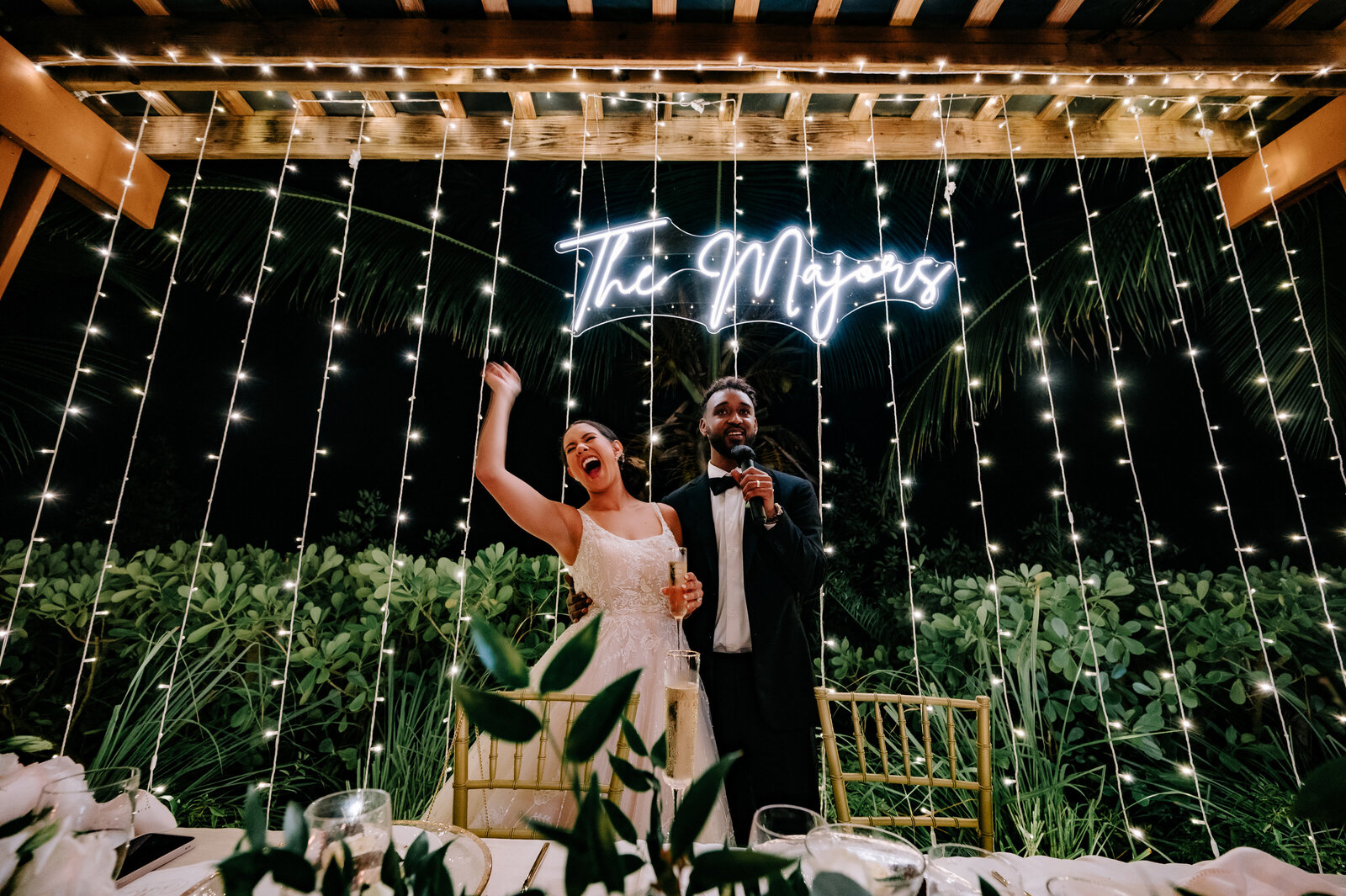 Bride and groom taosting under neon sign