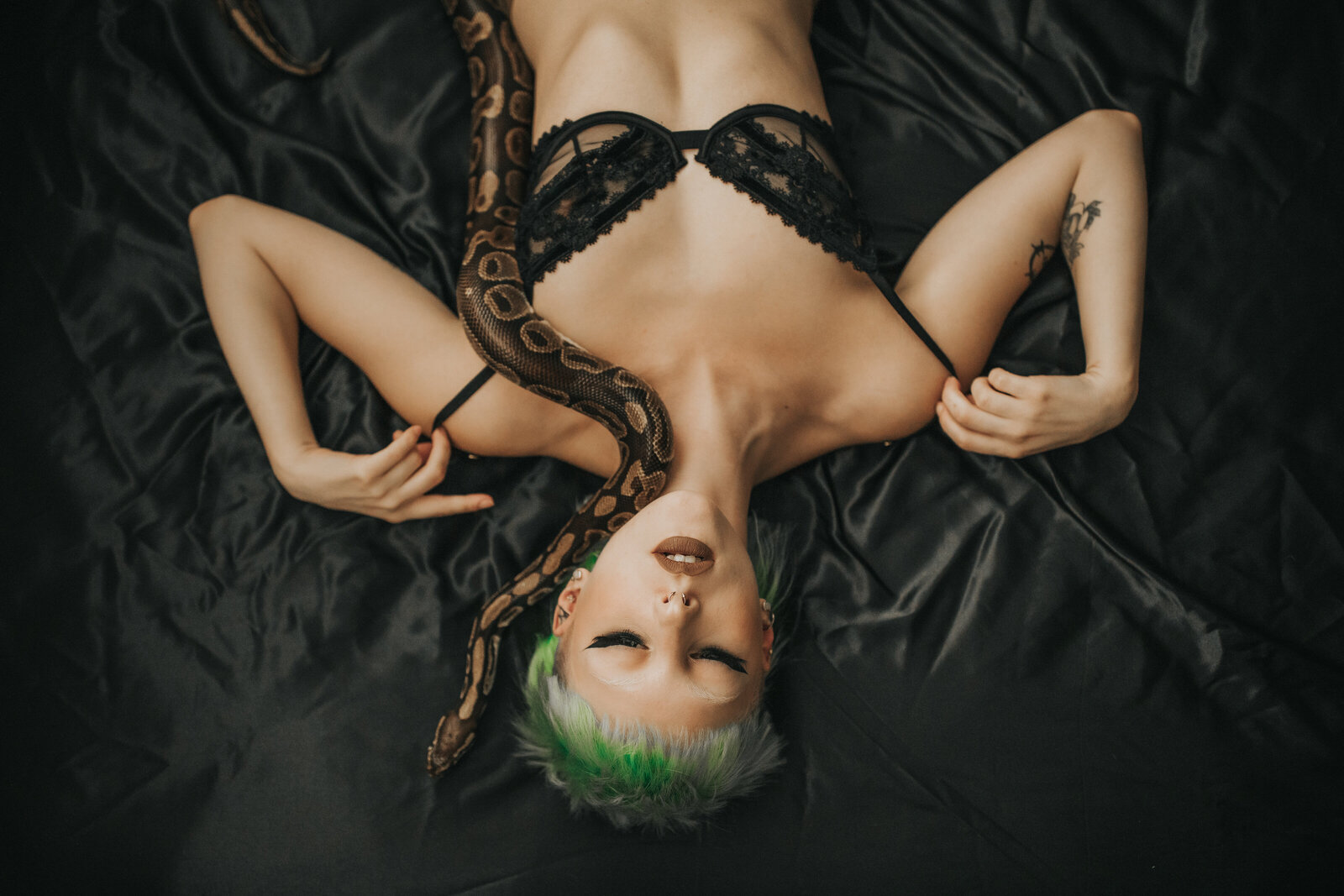 boudoir model posing with snake on bed