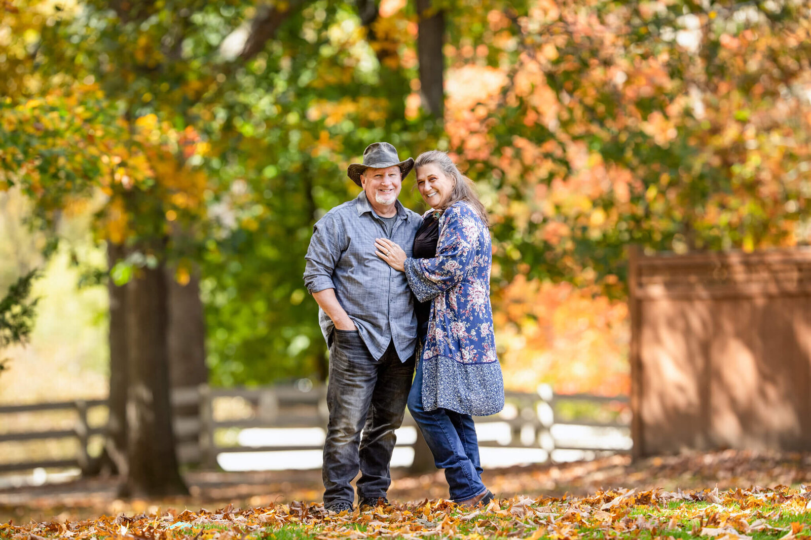 A couple in fall standing close and hugging looking towards camera