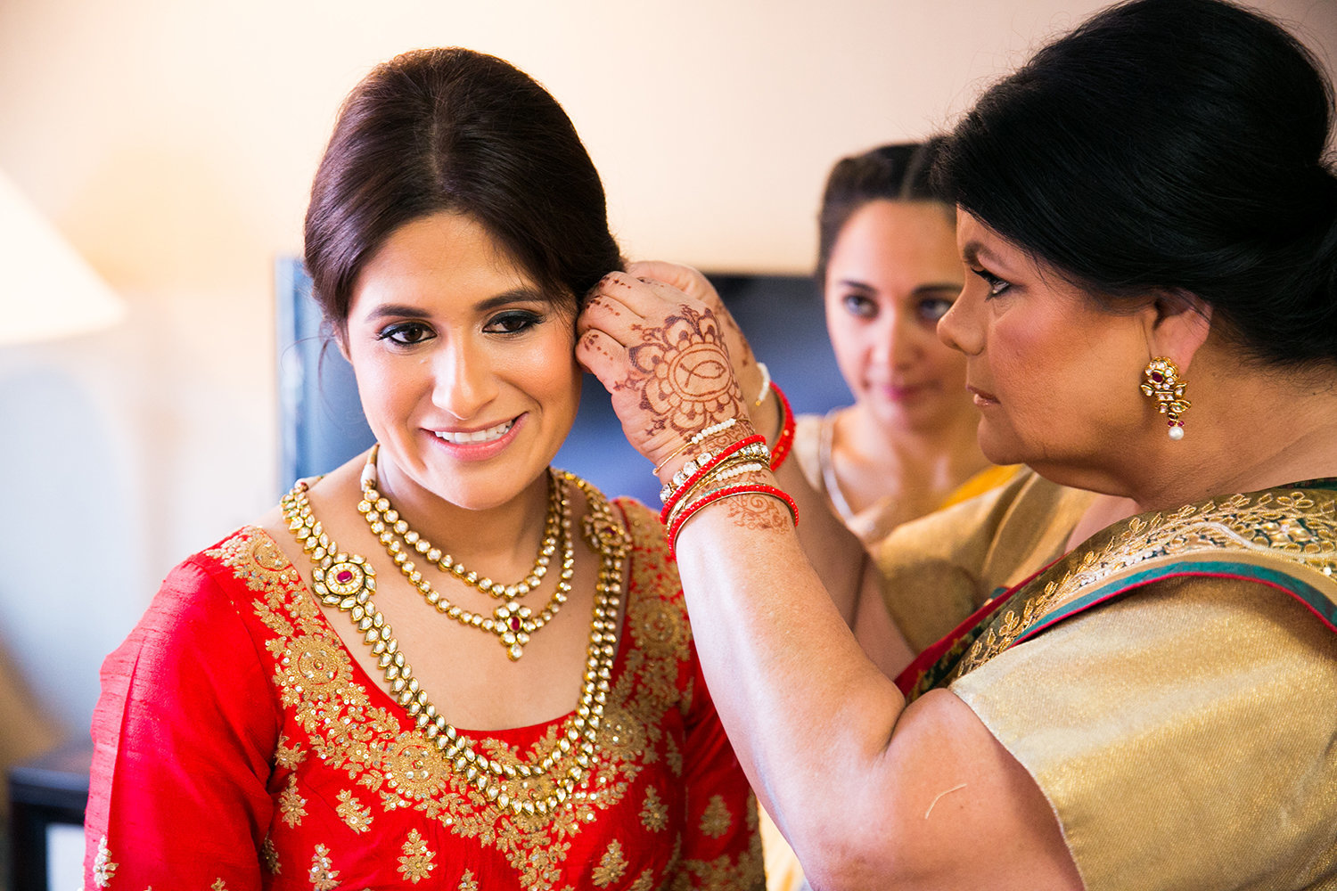 A bride is helped with her earrings by her mother
