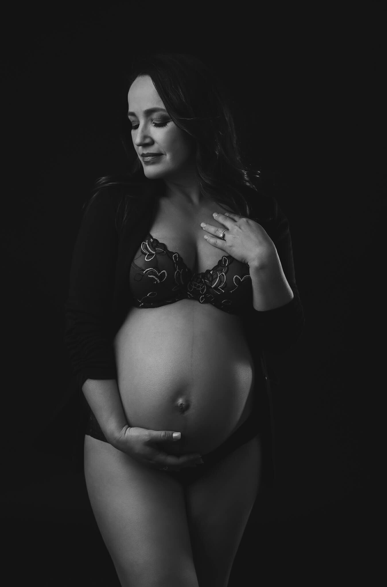 beautiful maternity portrait in black and white of pregnant woman wearing a set of lingerie and a blazer while touching her belly taken by Austin maternity photographer